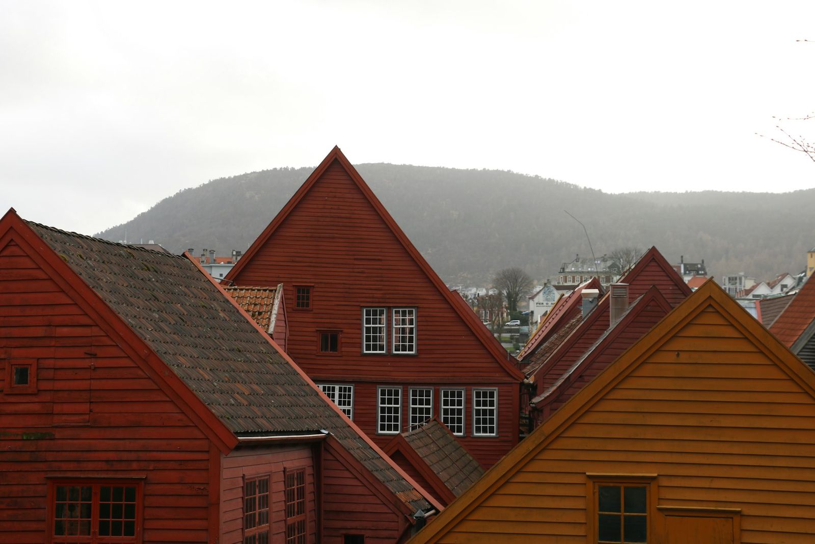 Rekke med rødmalte trehus på Bryggen i Bergen under en grå himmel